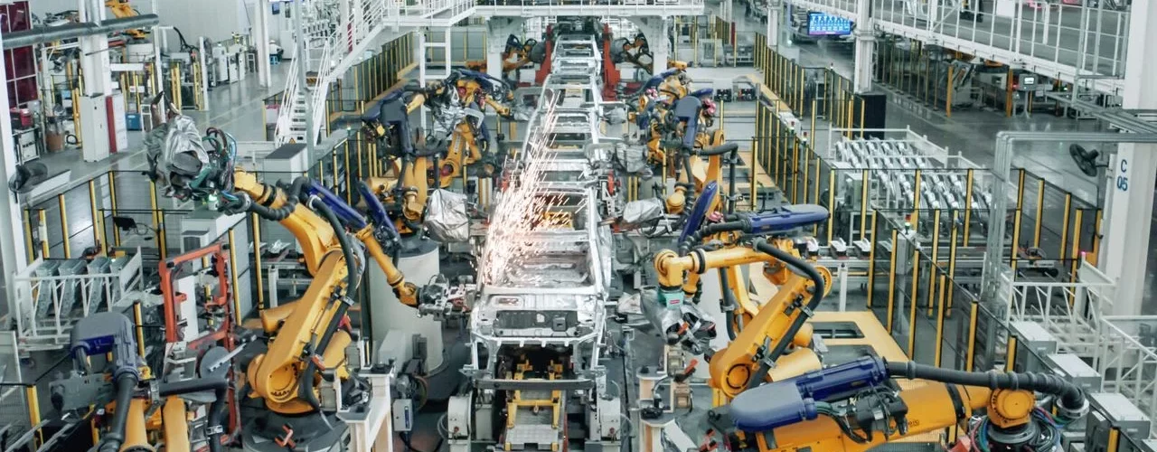 Фотография демонстрирует сборочный конвейер автомобильного завода, на котором частично приостановлена работа.