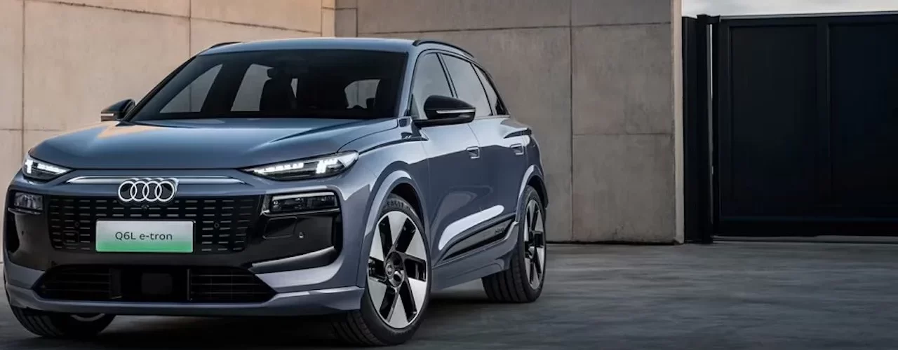 Новый электрический кроссовер Audi Q6L e-tron на фоне городского пейзажа