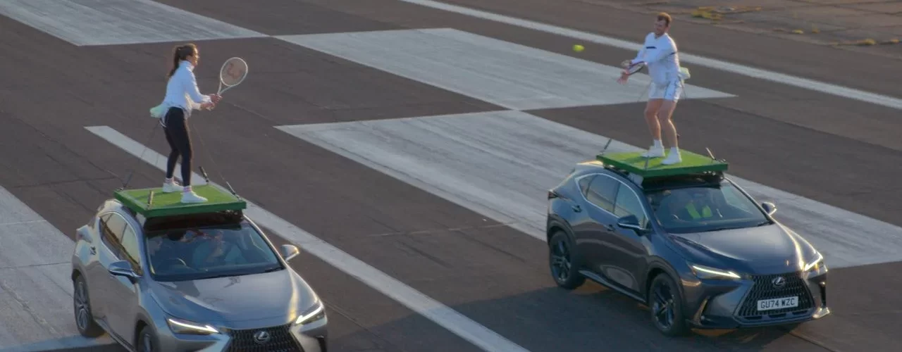 Два кроссовера Lexus NX едут по аэродрому, на крышах которых играют в теннис два человека