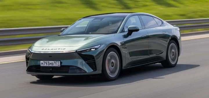 Спортивное гибридное купе Exlantix ES серебристого цвета на фоне городского пейзажа.