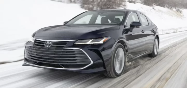 Toyota Avalon седан серебристого цвета на фоне городской застройки